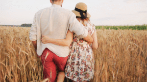 A view from behind of a couple walking arm-in-arm through a golden wheat field, illustrating a strong bond often discussed in relationship advice.