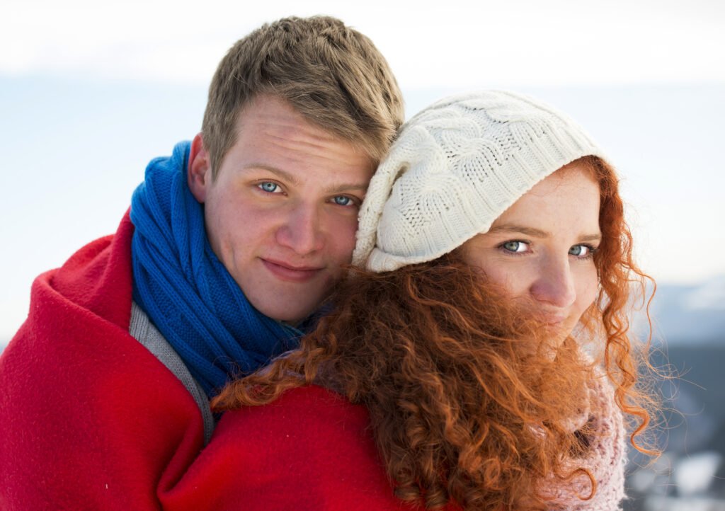 A close-up portrait of a young couple leaning together outdoors in winter, optimized as a Couple Style & Beauty image on home page of beautyrelationship.com.