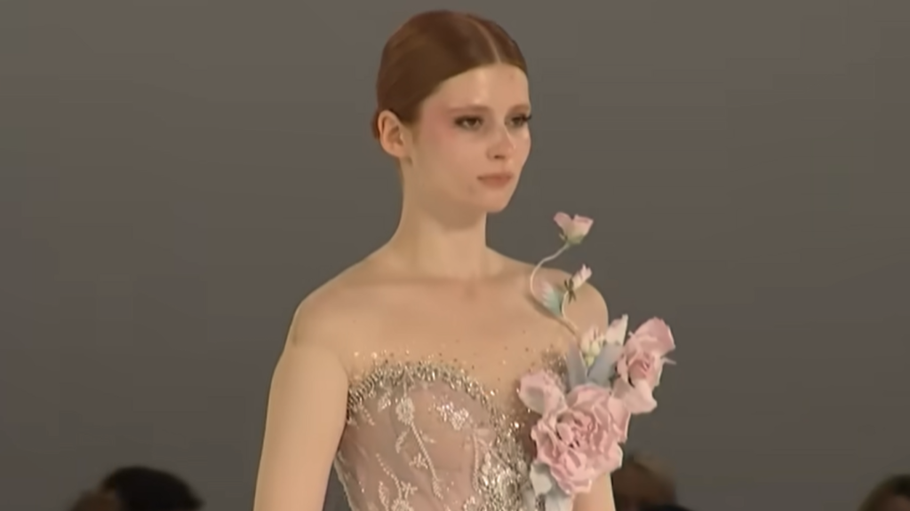 A runway model wearing an elegant floral-embellished gown, showcasing an upscale inspiration for dinner date night outfits and dressing for an anniversary dinner.