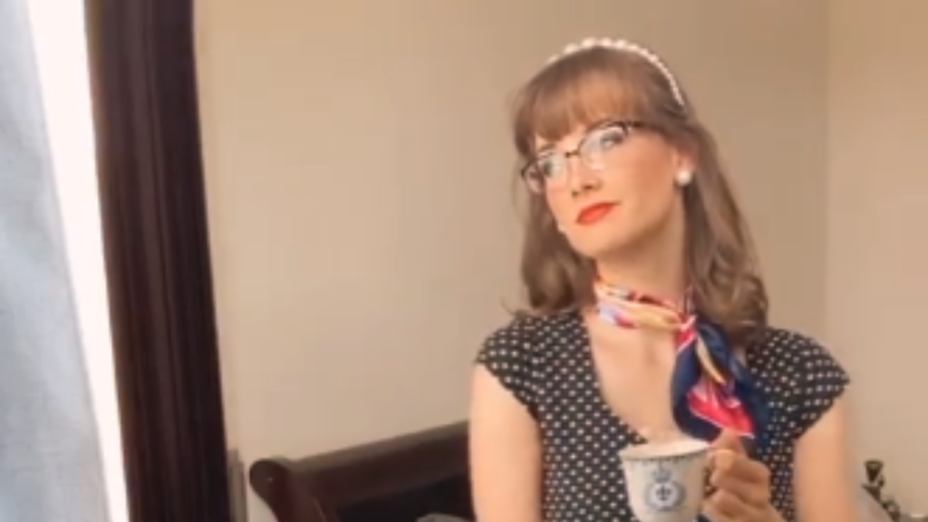 A woman dressed in a vintage-style polka dot top and a colorful silk neck scarf holding a teacup, showcasing a retro inspiration for dinner date night outfits.