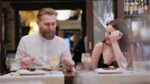 A stylish couple dining at an outdoor restaurant table, highlighting elegant dinner date night outfits.